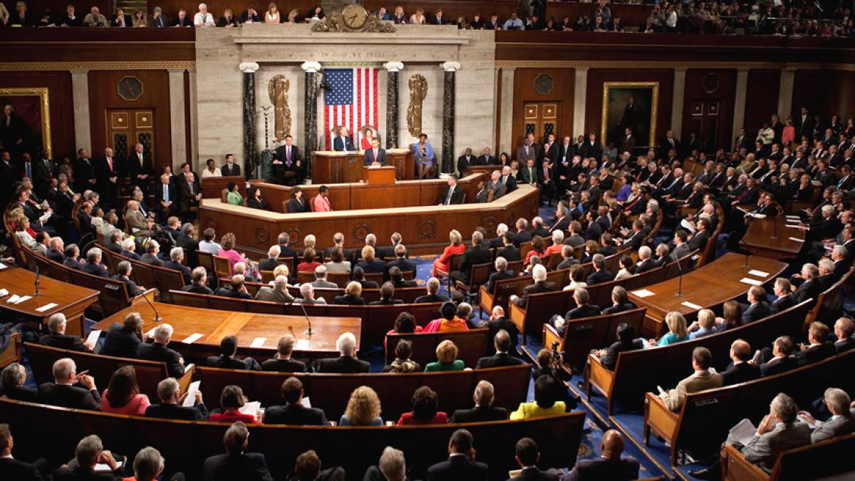 The United States House chamber during a recorded vote, the tally board lit along the wall.